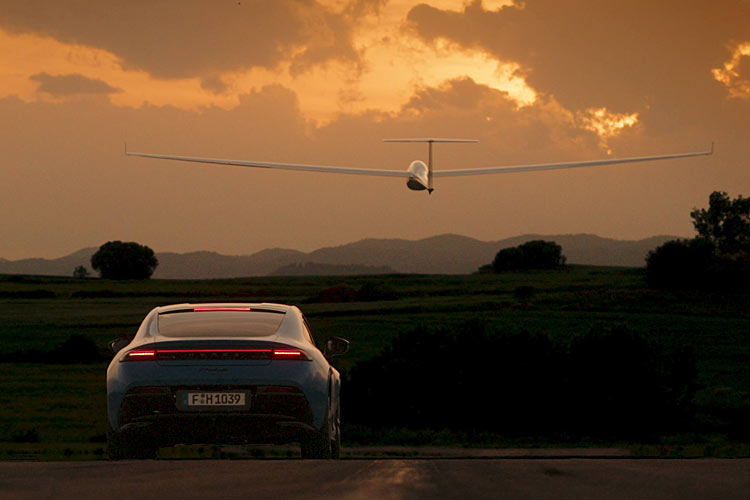 Ein Honda Prelude neuester Generation von hinten, dahinter bzw. darüber ein breites Segelflugzeug